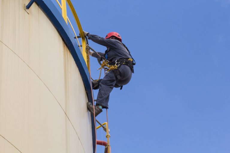 man on top of oil container